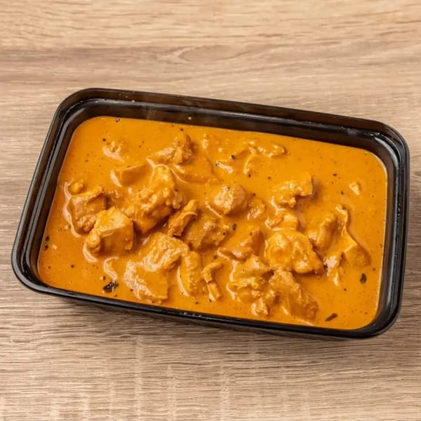 Kolapasi Indian Canteen's chicken tikka masala in a black takeout container on a wooden table.