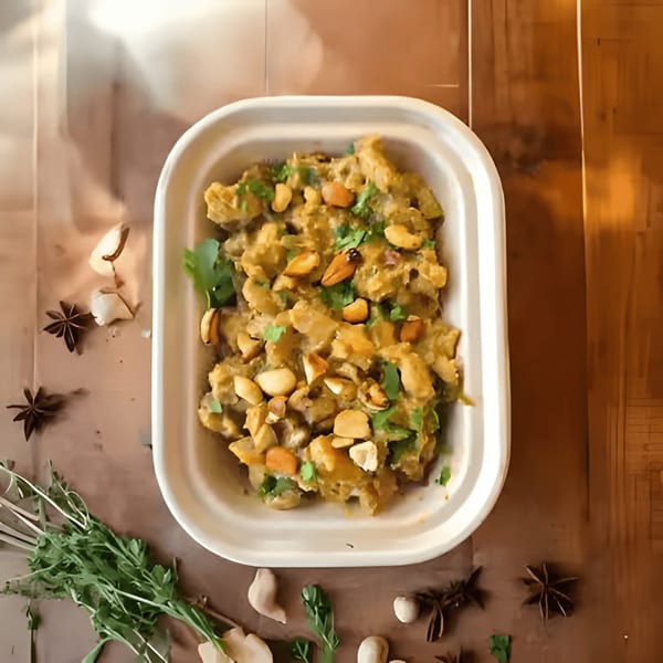 A takeout container filled with a creamy dish, topped with peanuts and fresh herbs, surrounded by spices.