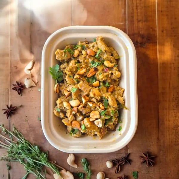 Kolapasi Indian Canteen's chicken curry with cashews and cilantro in a white takeout container.