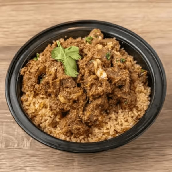 A black bowl filled with brown rice and a rich, dark meat dish, garnished with a sprig of cilantro.